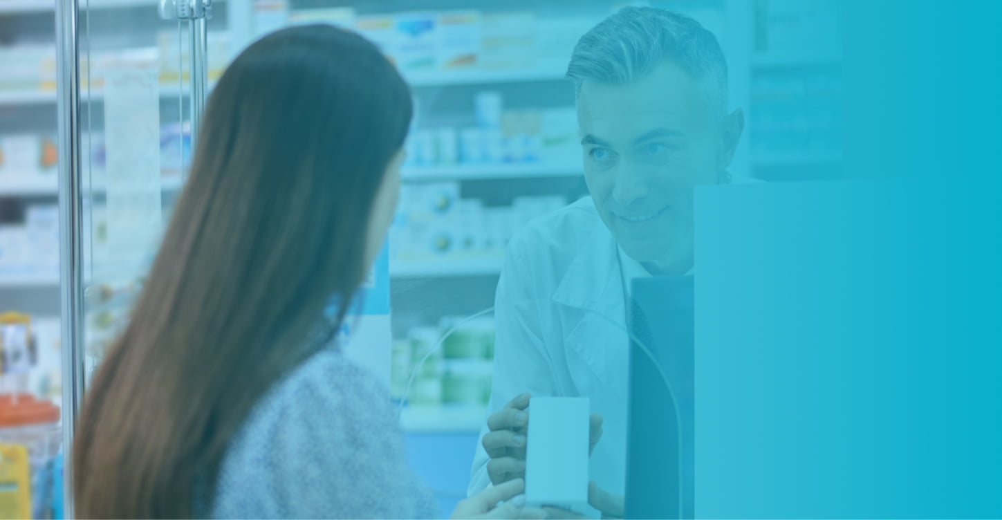 Woman at pharmacy counter speaking to pharmacist.